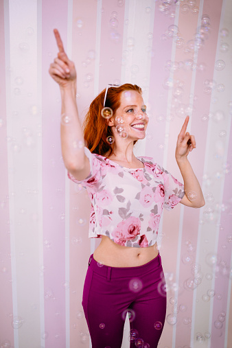 Young red head woman enjoys all the bubbles surrounding her