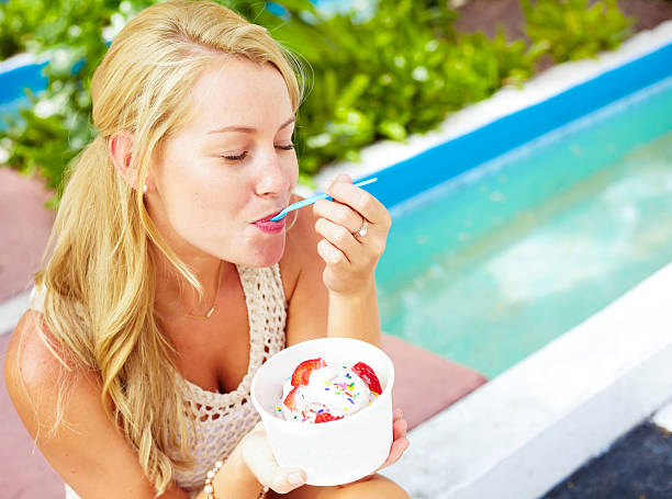 Young Woman Enjoying Eating Frozen Yogurt With Strawberries stock photo