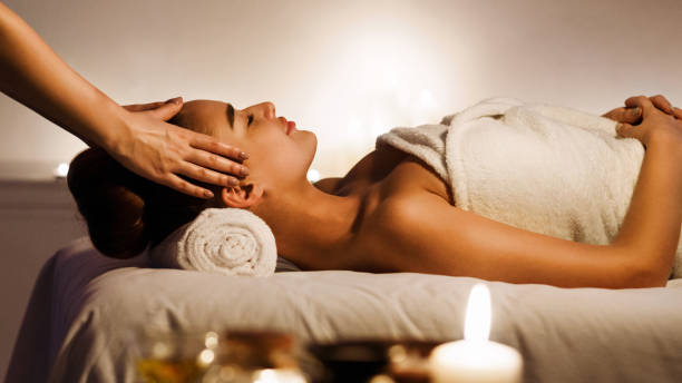 Young woman enjoying face massage in spa salon Young woman enjoying face massage with aromatic candles in spa salon massage stock pictures, royalty-free photos & images