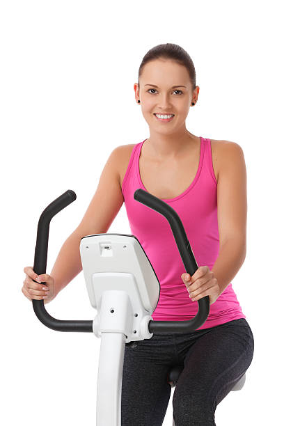 Young woman exercising on a bicyle against white background stock photo