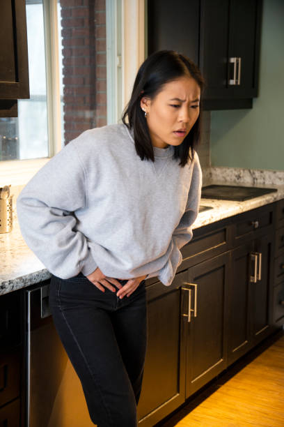 A young woman experiencing pelvic discomfort, she is grimacing in pain. A young woman experiencing pelvic discomfort, she is grimacing in pain. pelvic floor stock pictures, royalty-free photos & images