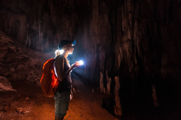jonge vrouw verkent grot - speleologie buitensport stockfoto's en -beelden
