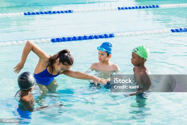 Young woman giving swim lessons to multi-ethnic group