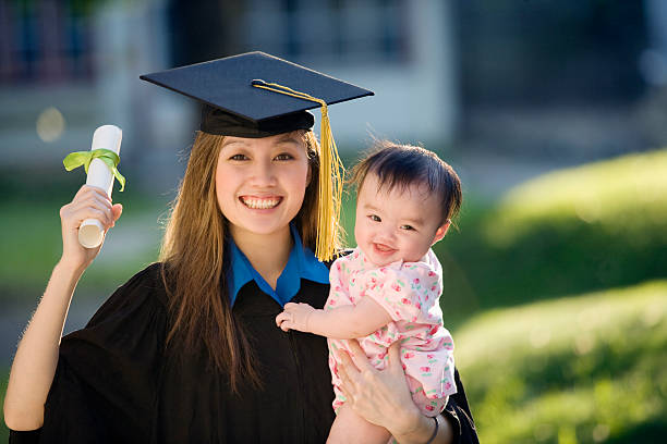 Young woman graduate holding baby stock photo