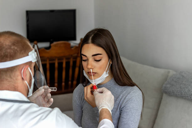 młoda kobieta o test wymazu nosa wykonane przez jej lekarza. - at home covid test zdjęcia i obrazy z banku zdjęć