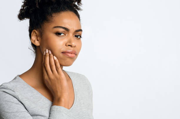 Young woman having acute teeth pain, touching her cheek Young afro woman having acute teeth pain, touching cheek, grey background, copy space human jaw bone stock pictures, royalty-free photos & images