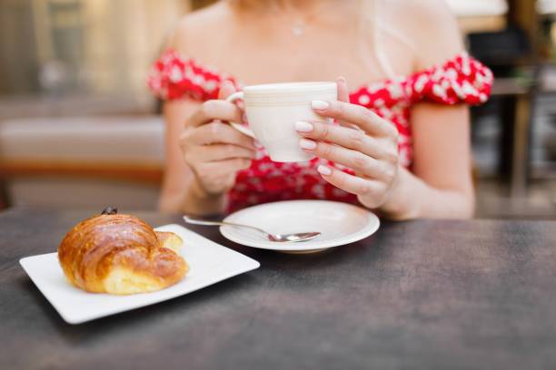 Young woman having italian breakfast with croissant and coffee a stock photo