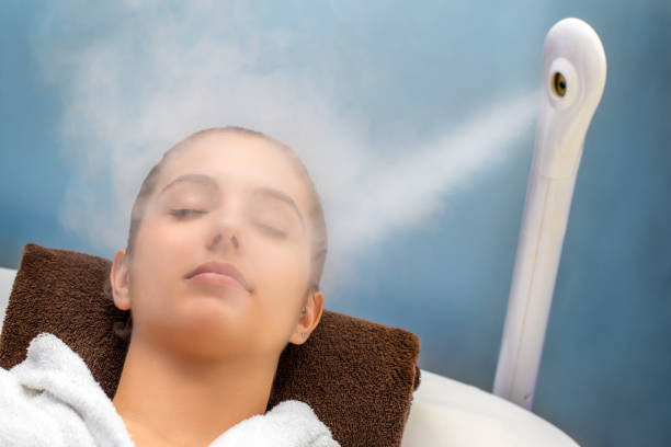 Young woman having thermal steam treatment on face. stock photo