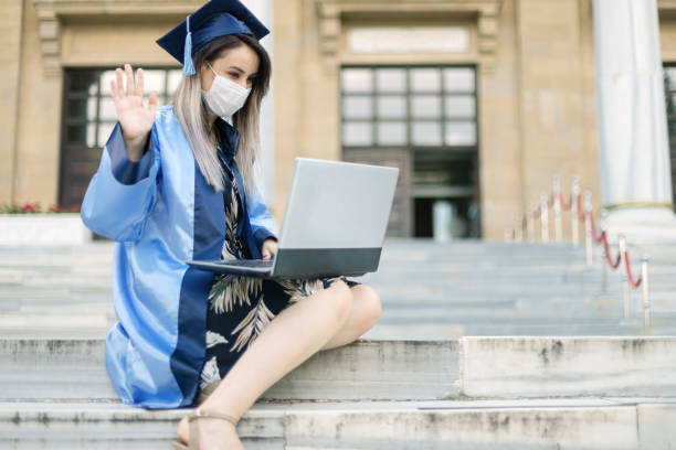 Young woman having video chats after her graduation ceremony Young woman having video chats after her graduation ceremony medical degrees online stock pictures, royalty-free photos & images