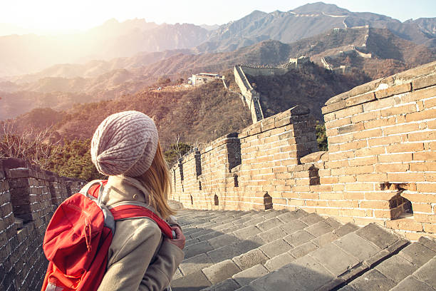 Young woman hiking the Great Wall of China Young woman on top of the Great Wall of China contemplating the beautiful landscape from high up. View of the wall going on the mountains for kilometres, majestic scenery of a winter day. mutianyu stock pictures, royalty-free photos & images