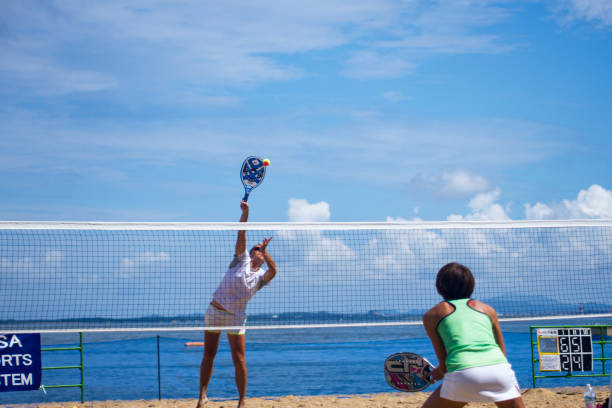 jovem bate em uma bola de tênis na praia - beach tennis - fotografias e filmes do acervo