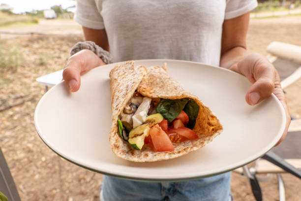 Young woman holding a Vegan wrap in a plate stock photo