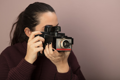 Young woman focusing on the viewer with a vintage camera