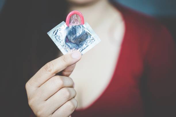 młoda kobieta trzymająca prezerwatywę w ładnej dłoni - hearing aids zdjęcia i obrazy z banku zdjęć