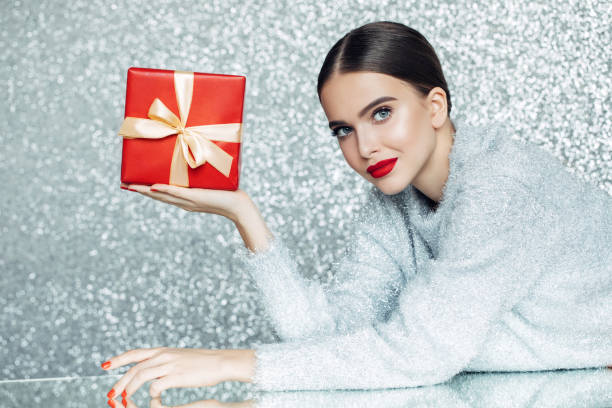 young woman holding gift box in her hands - woman holding a christmas gift imagens e fotografias de stock