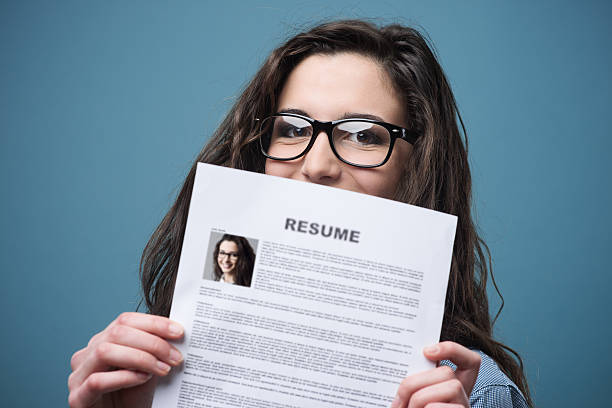 Young woman holding her resume Young woman hiding behind her resume resume stock pictures, royalty-free photos & images