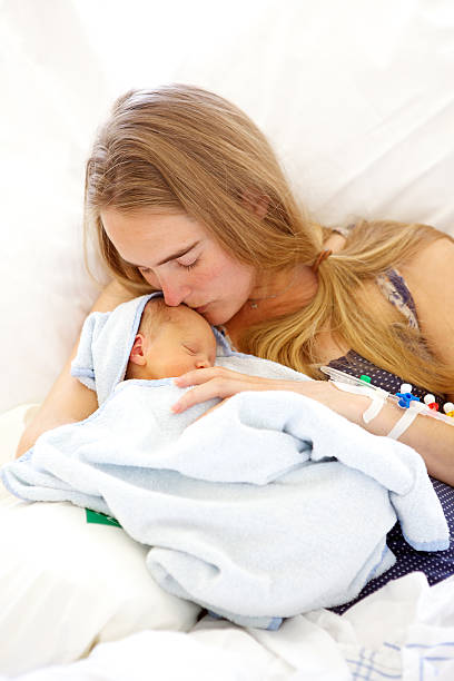Young woman holding her sleeping 1 day old daughter stock photo