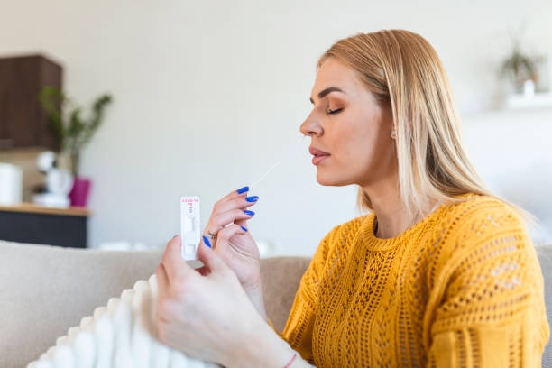 Young woman holding self testing self-administrated swab and medical tube for Coronavirus covid-19, before being self tested at home stock photo