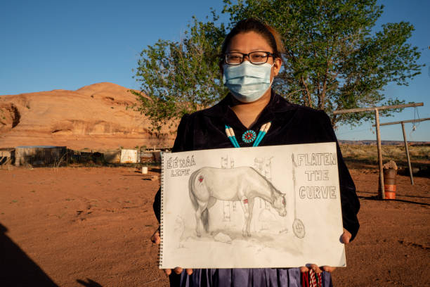 A Young Woman In A Face Mask, Holding A Drawing She Did To Help Her People Understand The Severity Of Covid19 A Native American teenager holding a drawing she hoped would help her people understand the danger of coronavirus to the Navajo people navajo nation covid stock pictures, royalty-free photos & images