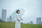 白いドレスを着た若い女性が雨の中で傘を持って歩いている