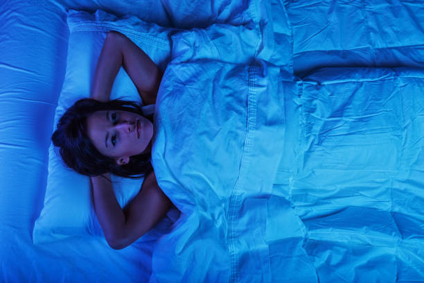 Young Woman in Bed with Insomnia Photo of a young woman lying in bed at night, wide awake with a case of insomnia insomnia stock pictures, royalty-free photos & images