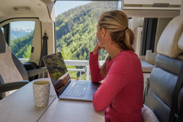 Young woman in her camper van works on laptop stock photo