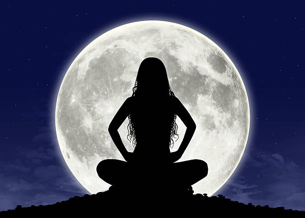 young woman in meditation at the full moon silhouette of a young beautiful woman with long hair in meditation posture with the full moon on the background, some graphics are provided by Nasa full moon stock pictures, royalty-free photos & images