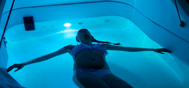 Young woman in sensory deprivation tank A relaxed young woman floating in a sensory deprivation tank. This alternative form of therapy is supposed to relax and clear your mind. floating on water stock pictures, royalty-free photos & images