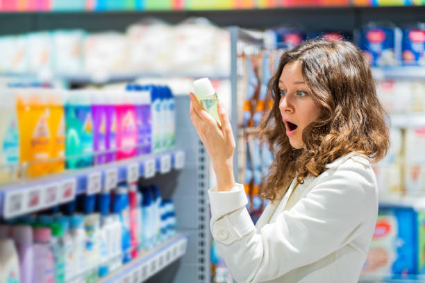 young woman in shock from the composition of baby shampoo, emotion of unpleasant surprise. the woman in the supermarket reading the label stock photo