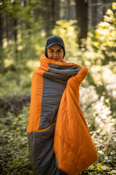 Young woman in sleeping bag standing in nature and looking at camera stock photo