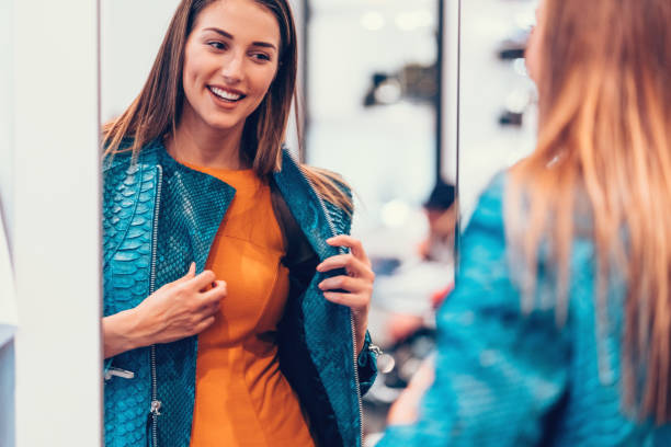 Young woman in the shopping mall enjoying a leather jacket Happy women in the clothing store getting dressed stock pictures, royalty-free photos & images