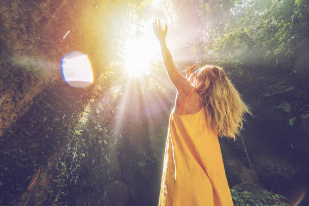 jonge vrouw in het tropisch regenwoud omhoog kijken naar mooie licht en de regendruppels met handen aan te raken. mensen reizen genieten van natuur en leven concept - rain woman sun stockfoto's en -beelden