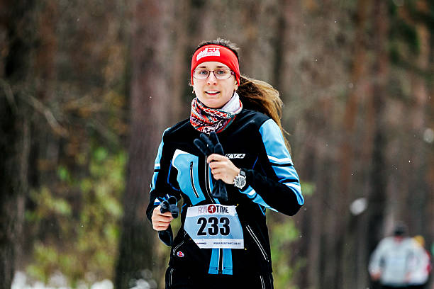 young woman in winter sport clothes running forest stock photo