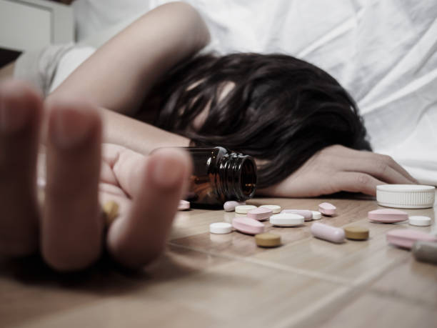 Young woman is lying on the floor with a lot of pills. Overdose and suicide concept. Young woman is lying on the floor with a lot of pills. Overdose and suicide concept. xanax pill stock pictures, royalty-free photos & images