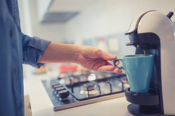 Young woman is making morning coffee in her kitchen. Young woman is making her morning coffee in her kitchen. She is wearing only a blue shirt. She is just waken coffee maker stock pictures, royalty-free photos & images