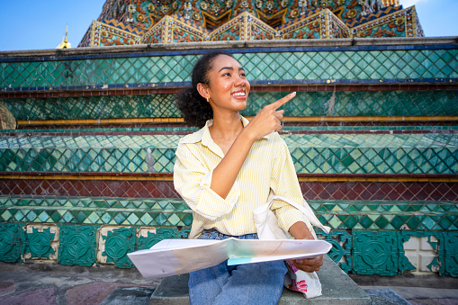 Young woman is solo traveller. She is enjoy to explore her world. The public temple is wat pho temple Famous place for travel and praying to budda. Asia culture.