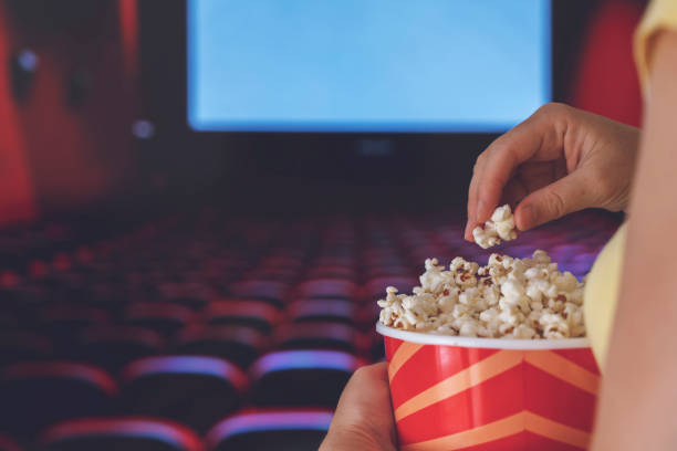A young woman is watching a movie and is eating popcorn at the cinema stock photo