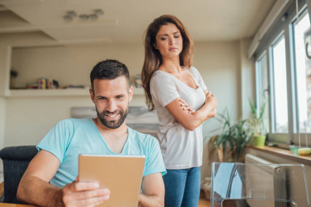 Young woman jealously looking at the smiling man using digital tablet Couple having relationship issues envy stock pictures, royalty-free photos & images