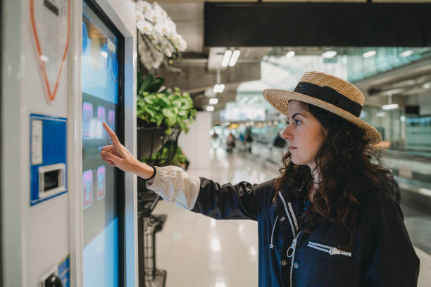 mujer joven mirando una pantalla de información en el aeropuerto - pantalla táctil fotografías e imágenes de stock