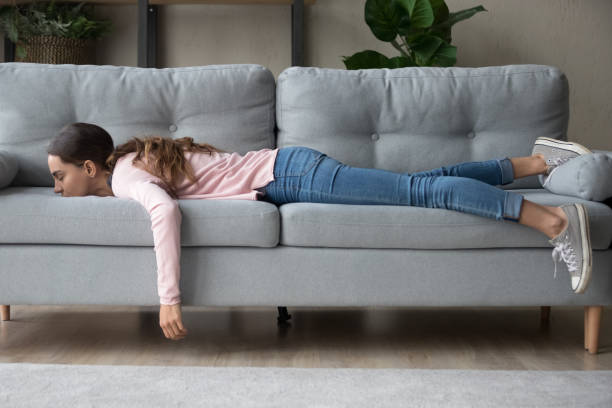Jonge vrouw liegen begraven haar gezicht in sofa voelt moe​​​ foto