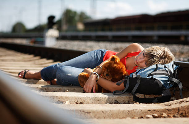 young woman lying on railroad tracks - teddy ray stok fotoğraflar ve resimler