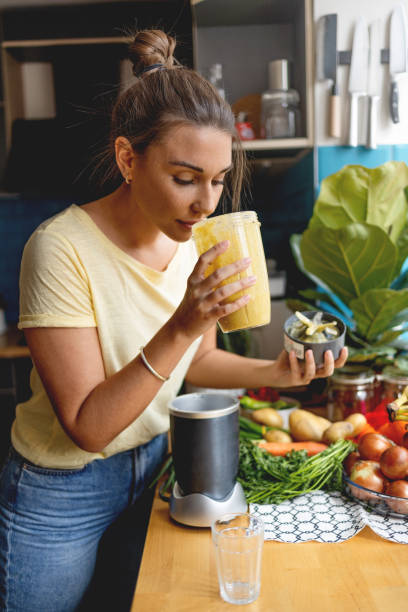 Young woman making a healthy smoothie for breakfast stock photo