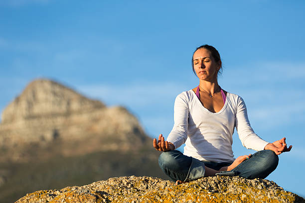 Young Woman Meditating on a Rock stock photo