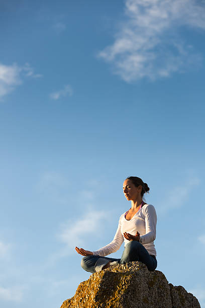 Young Woman Meditating While Facing the Sun stock photo