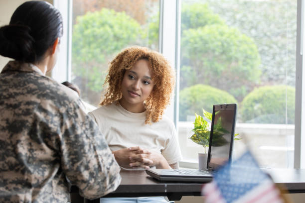 Young woman meets with female soldier in military recruitment office stock photo