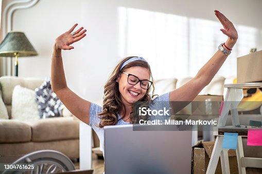 istock Young woman moving to a new apartment. A young beautiful woman sitting on the floor in a new house. A portrait of a happy woman who is in her new home unpacking things out of boxes. 1304761625