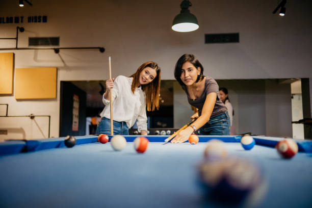 Young woman office workers playing pool in the office Image of two young woman office workers playing pool in the office. Playing pool with colleague on the break of the workday in the office. relax at office stock pictures, royalty-free photos & images
