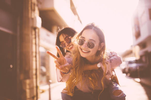 Young woman on piggyback ride doing the peace sign Hipster teenage girl on piggyback ride in the city doing the peace sign girlfriend stock pictures, royalty-free photos & images