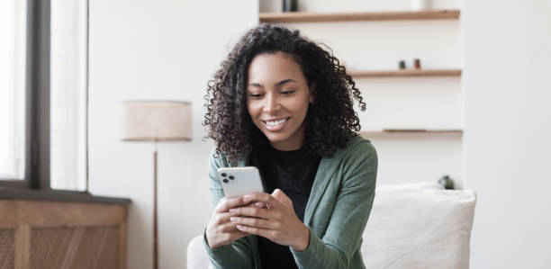 Young woman on sofa looking at smartphone, relaxing at home stock photo
