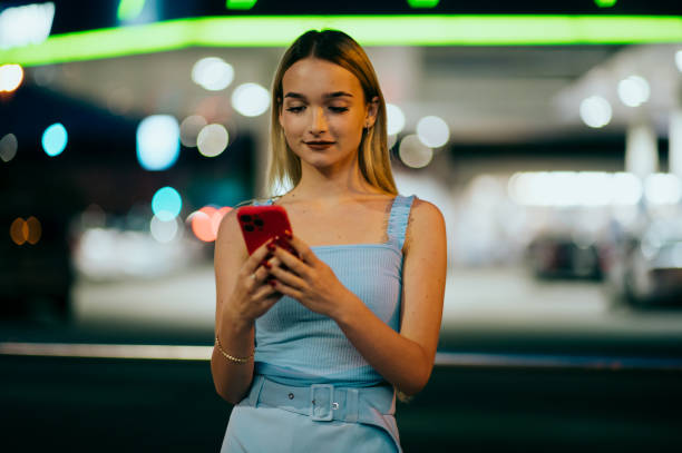 young woman on street using smartphone stock photo